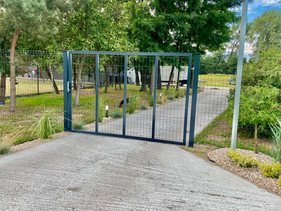 Dwuskrzydłowa brama panelowa w zielonym otoczeniu